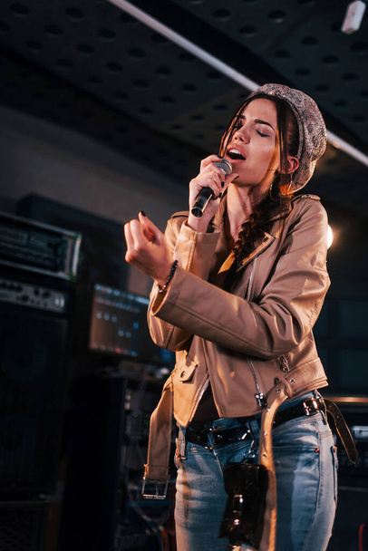 Young beautiful female singer rehearsing in a recording studio. - 写真・画像