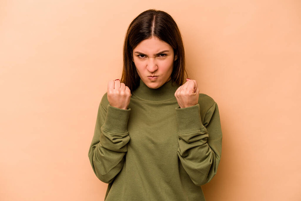 Young hispanic woman isolated on beige background upset screaming with tense hands. - Foto, imagen