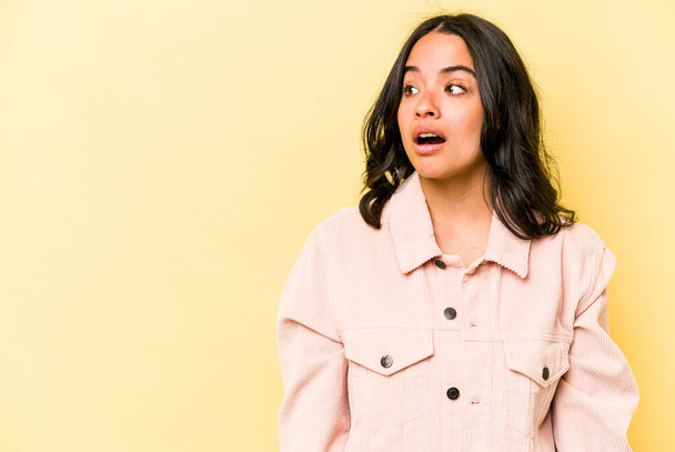 Young hispanic woman isolated on yellow background being shocked because of something she has seen. - Photo, Image