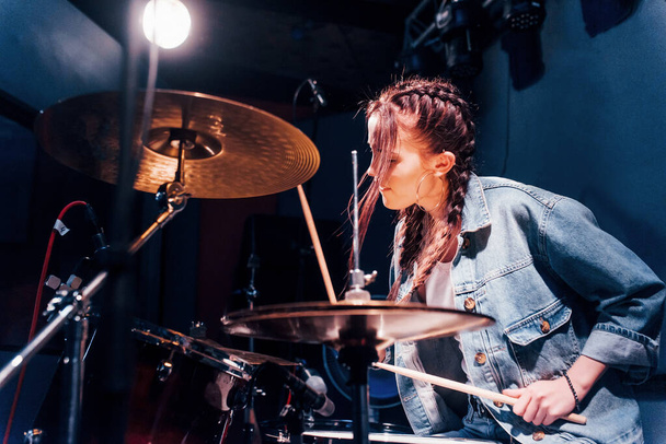 Plays drums. Young beautiful female performer rehearsing in a recording studio. - Foto, immagini