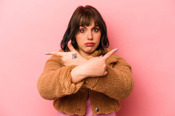 Young caucasian woman isolated on pink background points sideways, is trying to choose between two options. - Fotoğraf, Görsel