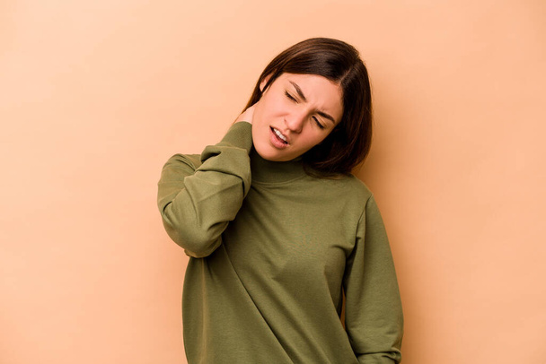 Mladá hispánská žena izolované na béžové pozadí trpí bolestí krku v důsledku sedavý životní styl. - Fotografie, Obrázek