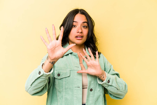 Young hispanic woman isolated on yellow background being shocked due to an imminent danger - Foto, Imagen