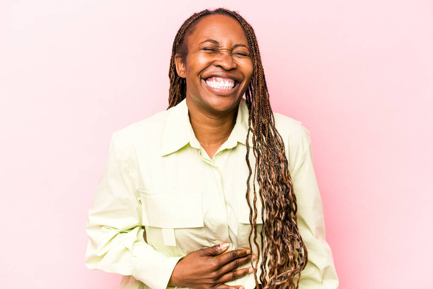 Junge afrikanisch-amerikanische Frau isoliert auf rosa Hintergrund berührt Bauch, lächelt sanft, Essen und Befriedigung Konzept. - Foto, Bild