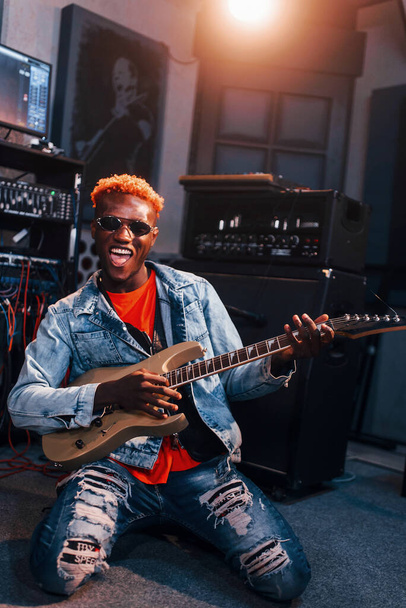 Plays guitar. Young african american performer rehearsing in a recording studio. - Valokuva, kuva