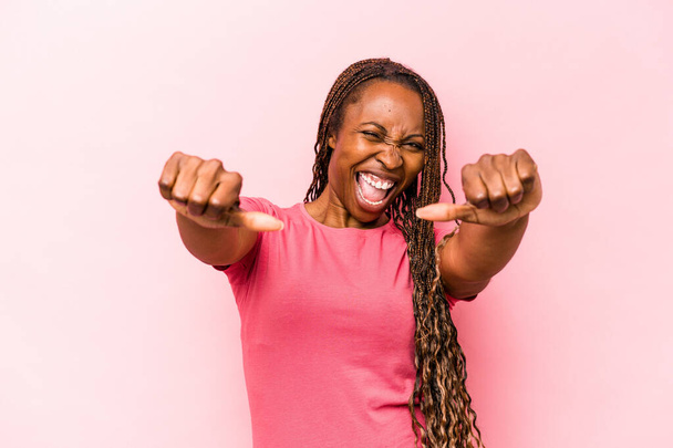 Молодая африканская американка, изолированная на розовом фоне, поднимает оба больших пальца вверх, улыбаясь и уверенно. - Фото, изображение