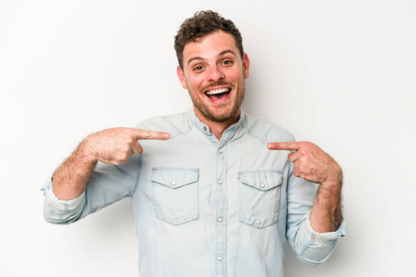 Young caucasian man isolated on white background surprised pointing with finger, smiling broadly. - Photo, Image