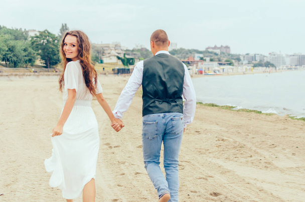 Wedding photo shoot by the sea. Husband and wife walking on the beach - Fotó, kép