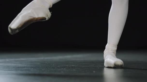 Close-up kobiece nogi w białych rajstopach i punts buty baletowe robi ćwiczenia taneczne ciągnąc rozciągającą się stopę nierozpoznawalny baleriny próby choreografii występujących na scenie w sali tanecznej - Materiał filmowy, wideo