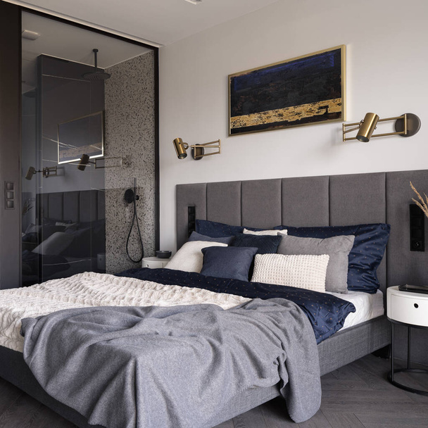 Modern and stylish bedroom with big and comfortable bed with nice bedclothes with contemporary designed shower cabin with glass wall - Fotoğraf, Görsel