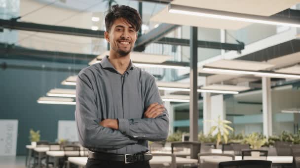Confident smiling indian business man male financial analyst employee professional worker stand in office with crossed arms arabian handsome adult investor posing look at camera happy face expression - Footage, Video