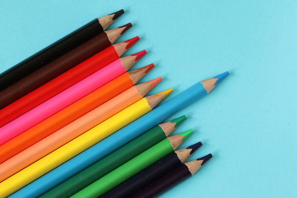 Kolorowe ołówki na niebieskim tle papieru. Zestaw kolorowych ołówków do rysowania. - Zdjęcie, obraz