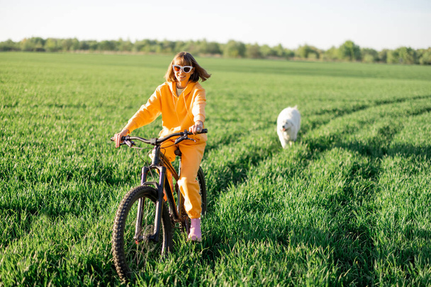 Woman rides a bicycle on a field - Фото, изображение
