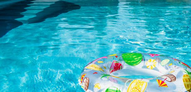 Concept de piscine d'été : Anneau gonflable avec impression tropicale flottant sur l'eau. - Photo, image