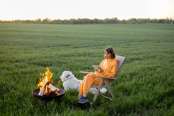 Mujer relajarse cerca de la chimenea con su perro en el campo - Foto, Imagen