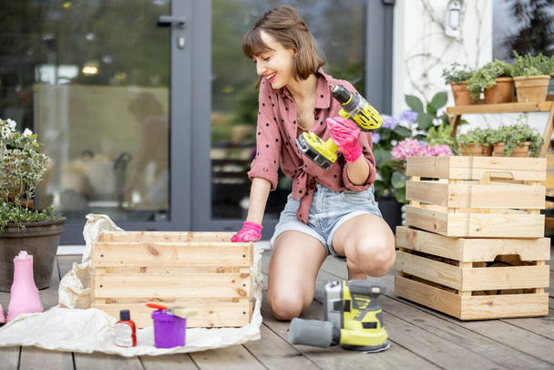 Housewife repairs wooden boxes on terrace - Photo, image