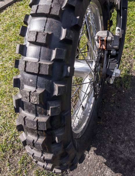 Una rueda de motocicleta enguro (para la conducción fuera de carretera y en carretera) con un primer plano en un neumático con un protector característico. - Foto, Imagen