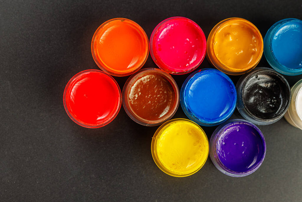 close-up background of opened small gouache paint jars on black surface - Fotoğraf, Görsel