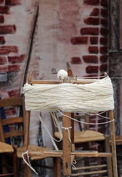altes hölzernes Spinnrad zur Herstellung von Wollknäueln durch Spinnen des Garnknäuels im alten ländlichen Landhaus - Foto, Bild