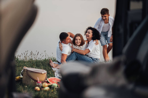 Вид з автомобіля Щасливі чотири члени Кавказької сім'ї даючи пікнік на відкритому повітрі озером, людиною і жінкою з двома дітьми підліткового віку на вихідний дорожній подорожі - Фото, зображення