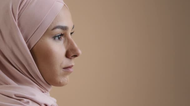 Close up profile portrait face of arab saudi woman muslim lady in stylish headscarf beautiful asian girl model businesswoman wear traditional islamic clothing confident pose look eyesight away indoor - 映像、動画