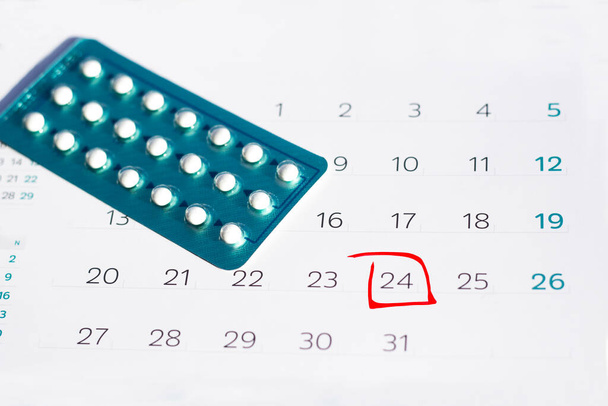 Píldoras anticonceptivas en el fondo del calendario. Concepto de cuidado del embarazo. - Foto, Imagen