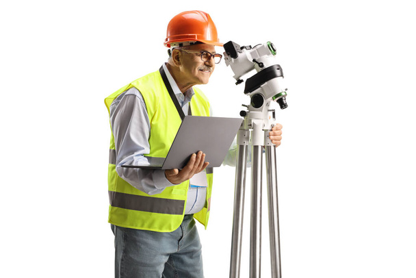 Geodetic surveyor measuring with a positioning station and holding a laptop computer isolated on white background - Fotoğraf, Görsel