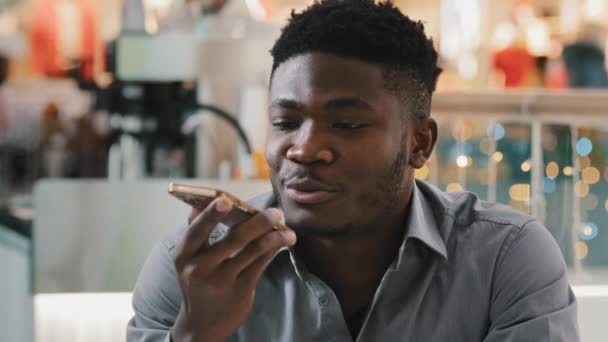 Közelkép fiatal afro-amerikai üzletember ül otthon rögzíti hang audio üzenet telefonon csevegés a közösségi hálón beszél kihangosító segítségével modern mobil asszisztens digitális technológia - Felvétel, videó