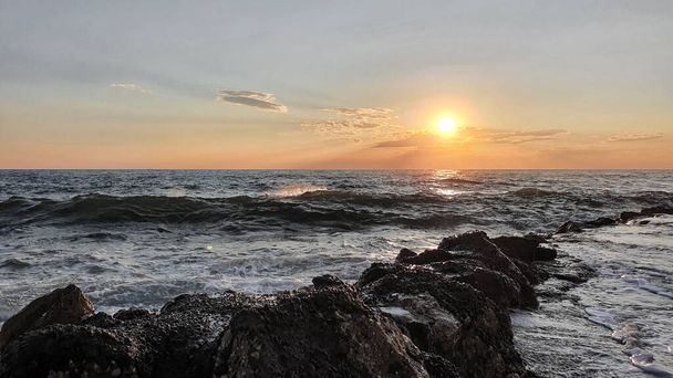 Цветной закат с большим солнцем под морскими волнами. - Фото, изображение