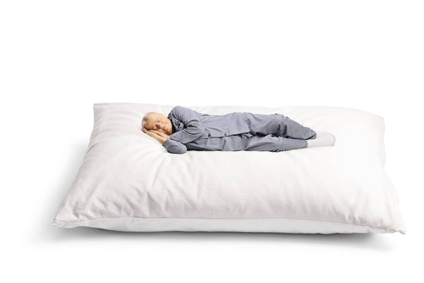 Elderly man in pajamas sleeping on a big pillow isolated on white background - Foto, Imagem