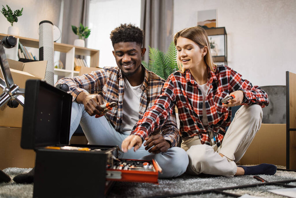Multi ethnic couple choosing repair tools at new home - Фото, изображение