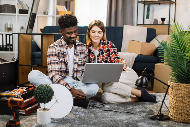 Relaxed couple sitting with laptop on floor at new house - Photo, Image
