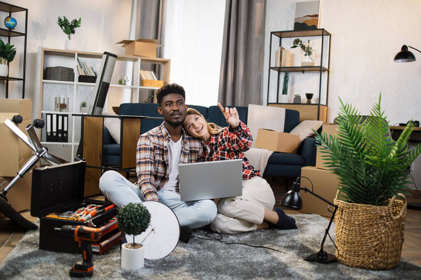 Diverse couple at new apartmemt using laptop - Foto, afbeelding