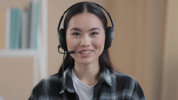 Close up portrait web cam view asian business woman wears headset talks to camera making distance online video conference call remote consultation female internet teacher explain advice chat from home - Кадры, видео