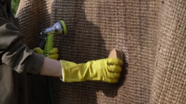 γυναίκα πλύσιμο και βρέξιμο ένα οικολογικό χαλί γιούτα σε εξωτερικό χώρο - Πλάνα, βίντεο