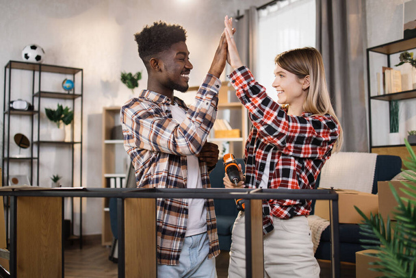 Happy diverse couple giving high five at their new flat - Fotografie, Obrázek
