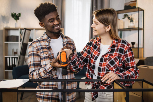 Happy multi ethnic couple with tools assembling furniture - Fotoğraf, Görsel
