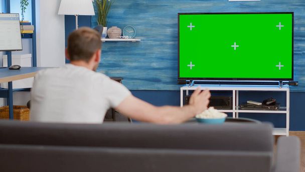 Sports fan watching game on green screen tv mockup encouraging favourite team while relaxing at home - Photo, Image