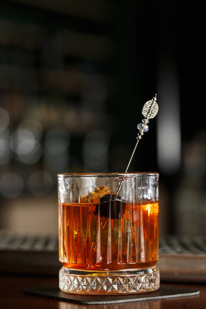 Old fashioned cocktail, consisting of Bourbon, Angostura Bitter, sugar cubes, a few drops of water, ice cubes, orange, maraschino cherry. - Photo, image