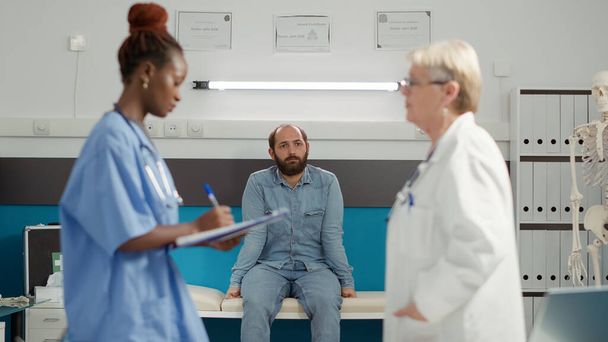 Paciente joven sentado en el gabinete médico y esperando los resultados del examen - Foto, imagen