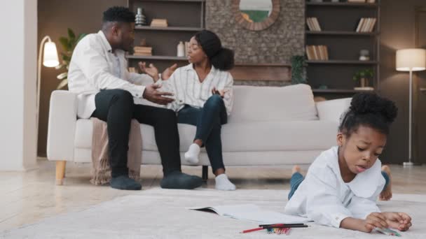 Afričané rodina naštvaný agresivní rodiče hádky konflikt domácí psychologické zneužívání spor sedí na gauči křičí smutný vyděšený dceruška leží na podlaze kreslení obrázek s tužkami - Záběry, video