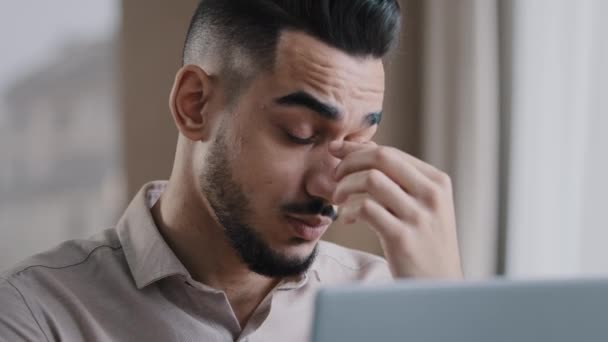 Wyczerpany młody milenijny biznesmen przepracowany mężczyzna pracownik masaż suche drażliwe oczy uczucie wzroku po użyciu komputera zmęczony latynoski facet ból głowy złe widzenie problem - Materiał filmowy, wideo