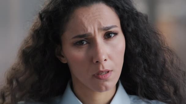 Mladá vážná hispánská brunetka žena s kudrnatými vlasy zvídavý výraz obličeje položit otázku, co arabský přemýšlivý žena podnikatelka pracovník, aby pochybnosti emoce při pohledu na kameru znak nejistoty - Záběry, video