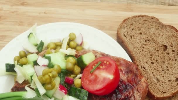 chicken leg cooked on fire with leek, brown bread and spring salad, close-up, on a wooden board - Footage, Video
