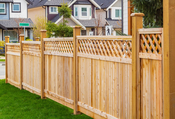 Красивый деревянный забор вокруг дома. Деревянный забор с зеленой лужайкой. - Фото, изображение