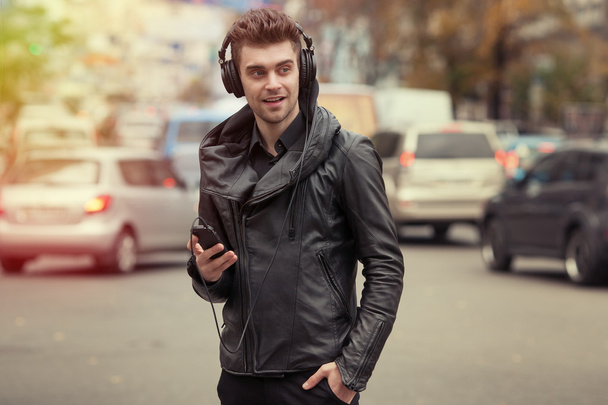 Mann mit Kopfhörer auf der Straße. Stehen mit Telefon in der Hand - Foto, Bild