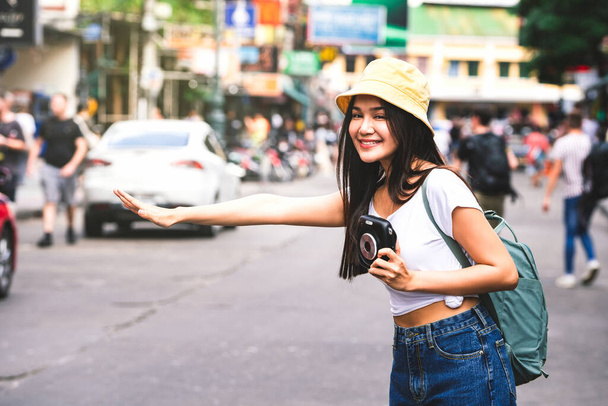 Nuori aasialainen matkustaja onnellinen nainen valkoisessa paidassa reppu. Pidä pikakamera. Liputa taksi matkailua varten. Khaosan Road tausta. Bangkok City, Thaimaa - Valokuva, kuva