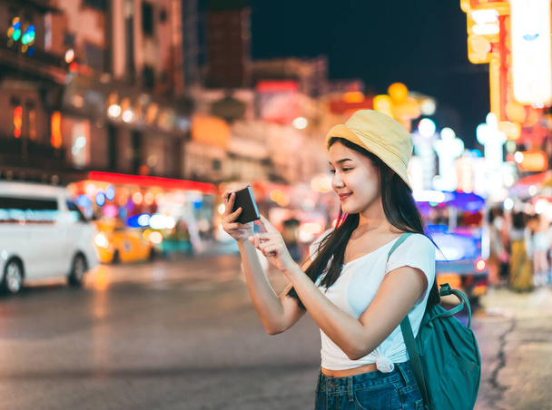 Mladý dospělý asijské cestovatel šťastný žena v bílé košili s batohem. Samostatné prohlídky s moderní technologií koncepce. Používá chytrý telefon. Vedle čínského městečka. Bangkok City, Thajsko - Fotografie, Obrázek
