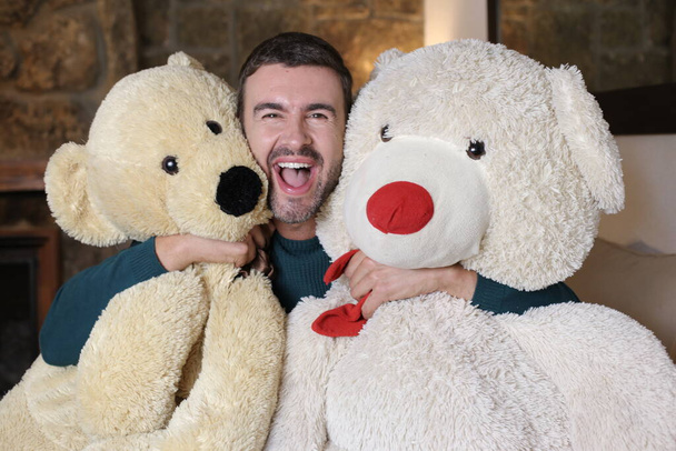 close-up portrait of handsome young man holding teddy bears at home - Foto, Imagem