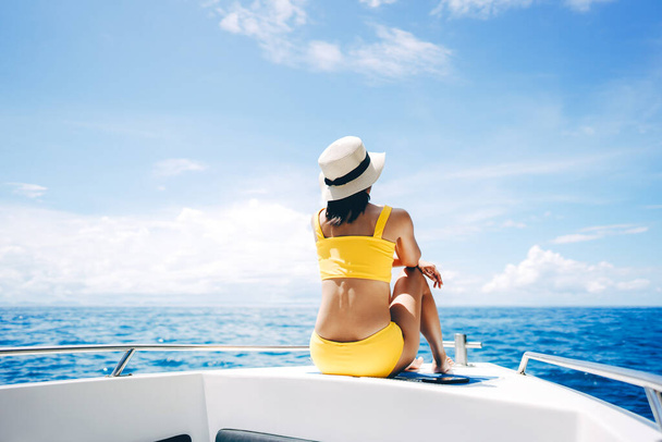 若い大人の旅行の女性の後部ビューは、セーリングボートに座って黄色のビキニ青い空と海を身に着けています。夏休みの国内旅行。タイのプーケット - 写真・画像